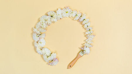 Brush draws a round frame of white flower heads with chrysanthemum. copyspace. Template for text or design. Holiday greeting card. yellow background.の写真素材