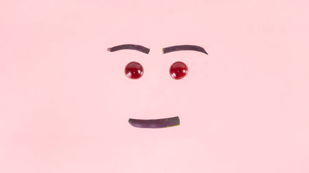 Face made from purple asparagus beans and cherries. Concept of berries season and proper nutrition. pink background.の写真素材