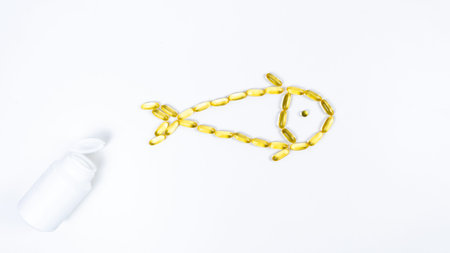 Fish made from yellow capsule transparents with fish oil, Omega 3 near open white tube. White background. Concept of maintaining and improving health.の写真素材