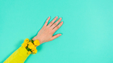 Natural flowering branches covered with yellow flowers grow from yellow sleeve on woman's arm....