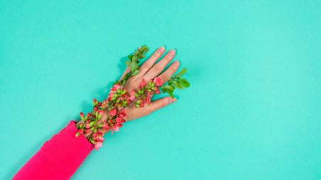 Natural flowering branches covered with red flowers grow from red sleeve on woman's arm....