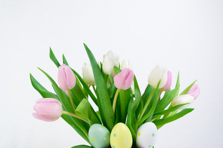 Easter eggs near a bouquet of spring natural fresh tulips flowers. Easter greeting card. White background. Copy space.の写真素材