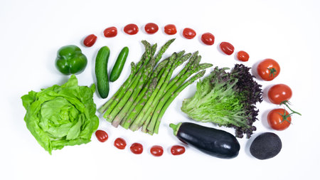 Green, purple vegetables and tomatoes on a white background. Asparagus, lettuce, cucumbers, peppers,...
