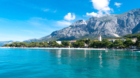 Serenely calm Adriatic Sea in summer season. Clean small-pebble beach on a sunny morning. Promajna, Croatia. Magnificent pine trees grow by Adriatic sea. Vacation location.の写真素材