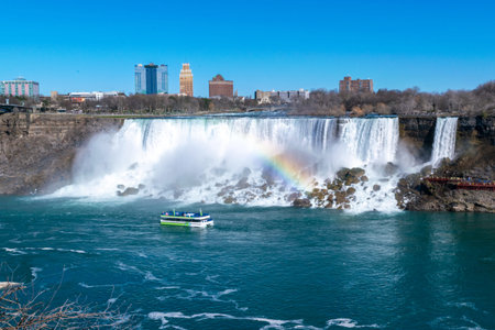 Beautiful view of American Falls and Bridal Veil Falls is waterfalls that makeup Niagara Falls. Rainbow and tourist ship in the foreground. View from Canadian side to United States side. Sunny day. Blue sky.の写真素材