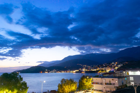 Twilight landscape of a resort Himare town located in a bay at the foot of the mountains. The village is beautifully lit by lanterns after sunset. Ionian sea. Albania.の写真素材