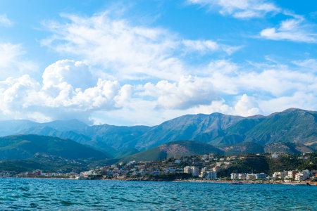 Beautiful summer cloud landscape of beach town of Himare at foot of mountains on border of Ionian...