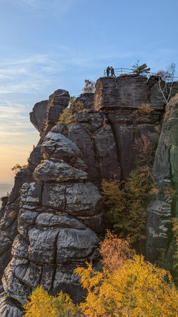 Silhouettes of tourists on the observation deck at the top of Lilienstein hill. Atmospheric beautiful autumn sunset landscape. Golden autumn. Saxon Switzerland National Park. Germany.の写真素材