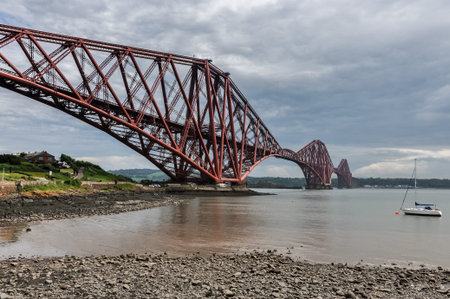 Famous Forth Bridge in Edinburgh, Scotland with a small boat in background.