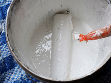 Paint roller dipping in white paint.の写真素材