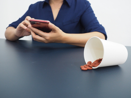 Medicine pills with woman using smart phone.の写真素材