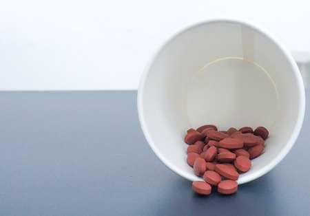 Red pills in white paper cup.の写真素材