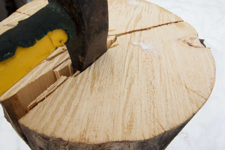 Splitting a pine log for winter firewood with an axeの写真素材