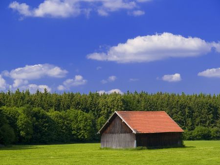 meadows and hut under a blue skyの写真素材