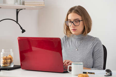 Natural blonde woman looking at the screen of her laptop while video call. Remote internet online classes. Isolation time. Pandemic threat. Virus outbreak.の写真素材