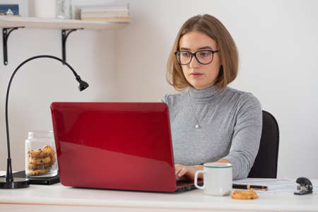 Natural blonde woman looking at the screen of her laptop while video call. Remote internet online classes. Isolation time. Pandemic threat. Virus outbreak.の写真素材