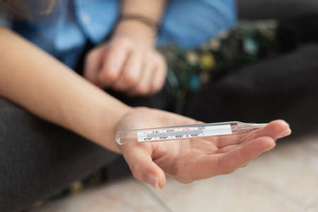 Medical thermometer in the palm oh hand close-up. Blurry background.の写真素材