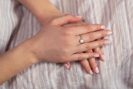 Woman hands with golden ring on the middle finger against light background.の写真素材