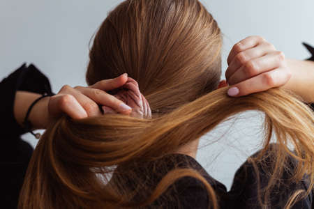 Natural blonde woman doing a ponytail, holding her hair, stop motion, back view,の写真素材
