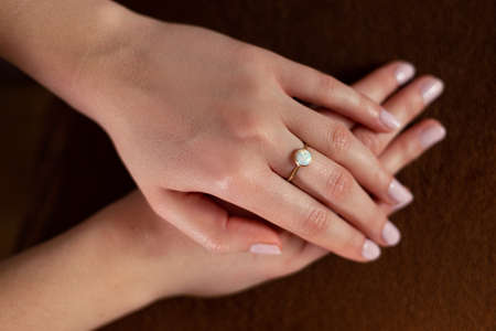 Woman's hands with gold ring on her middle finger against dark background.の写真素材