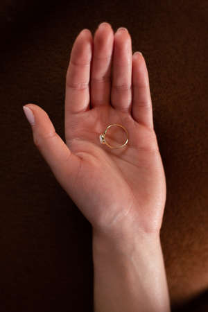 Beautiful ring on an open hand of a woman. Dark background. Vertical photo.の写真素材