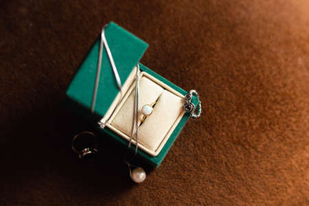 Open bottle-green jewelry box with rings and pearl necklace.の写真素材