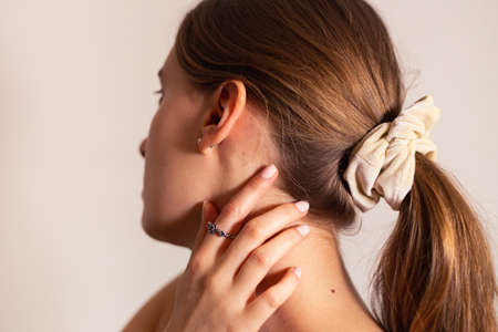 Blond woman with her hand touching her neck, rose ring on her finger. Side view.の写真素材