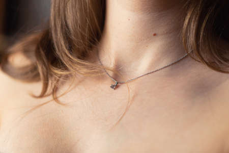 Nude blonde woman's neck with silver necklace close-up.の写真素材