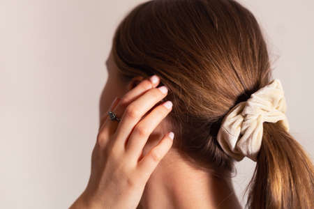 Natural blonde woman with her hand touching her ear, hair in ponytail.の写真素材