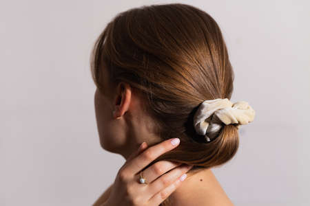 Natural blonde woman holding hair in ponytail with scrunchie. Side perspective.の写真素材