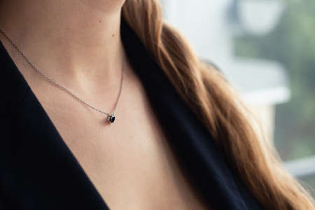 Silver necklace with black stone pendant on woman's neck, black blazer, elegant style. close-up. Business power woman, successful people, side viewの写真素材