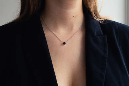 Silver necklace with black stone pendant on woman's neck, black blazer, elegant style. close-up. Business power woman, successful peopleの写真素材