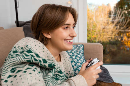 Close-up beautiful blond woman enjoying her time with video game, perfect smile, being happy, virtual reality world, beige couch, safe environment, cozy vibe, self isolating, winter, christmas theme,の写真素材