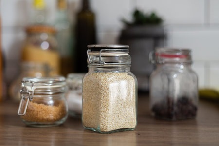 Side view of glass jar with sesame seeds, ingredients, kitchen equipment, vegetarian food, nutrition, preparing healthy meal, additives to the dish, recipe cooking, rustic styleの写真素材