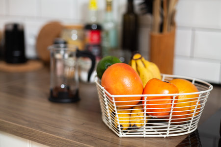 Fresh fruits in metal basket, bowl, bright kitchen, vegeterian food, preparing meal, oranges and bananas, wooden worktop, rustic style, dietの写真素材