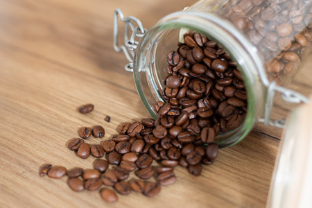 Coffee beans falling out of a glass jar close-up, top down view, rustic style, interior kitchen design, retro, warm tonesの写真素材
