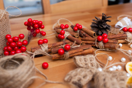 adorable, cute cinnamon sticks with red breads and cones, warm tones, christmas decorations, diy staff, handmade, winter theme, mood, preparing to eve, side view with blurry foregroundの写真素材