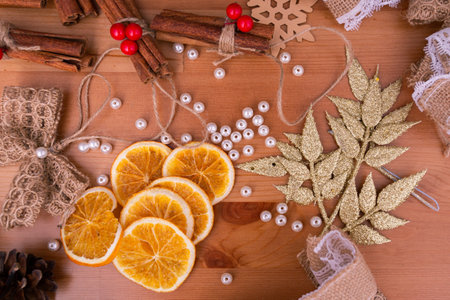 Top down view of rustic style handmade, diy, christmas decorations, cinnamon sticks, dried oranges, wooden table, warm tones, white beads, banner, backgroundの写真素材