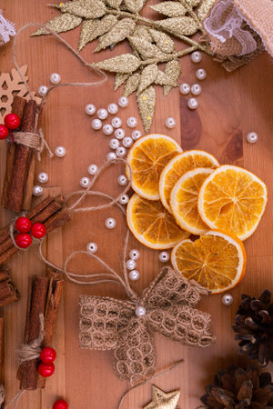Top down view of rustic style handmade, diy, christmas decorations, cinnamon sticks, dried oranges, wooden table, warm tones, white beads, banner, background, vertical photo,の写真素材