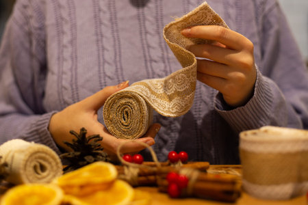 Woman holding decorative ribbon doing diy, christmas ornaments, decorations rustic style winter...