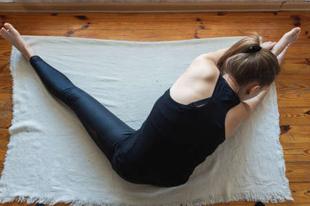 Blonde woman stretching to right side on the floor. Top down perspective. Yoga pose. Home exercises during quarantine.の写真素材