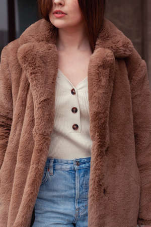 Brunette woman dressed in brown fur coat and blue jeans. Close-up. Fashionable attire. Warm clothes. Influencer style.の写真素材