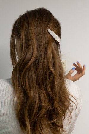 Young blond woman from behind with long loose wavy hair, clipped with pearly snap hair clip.の写真素材