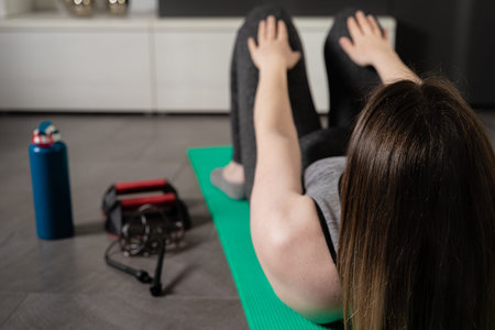 View of a young woman on her back doing sit-ups with the sports