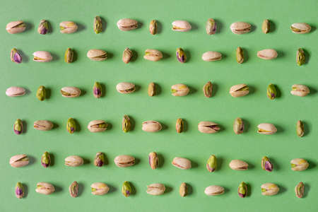 Pistachios isolated on green background, top view. Flat lay patternの写真素材