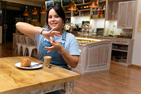 Young woman drinking coffee, making the sign of union.の写真素材