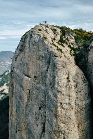 People jumping on the top of a large rock