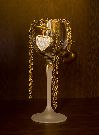 Glass of wine and gold heart necklace on a dark backgroundの写真素材