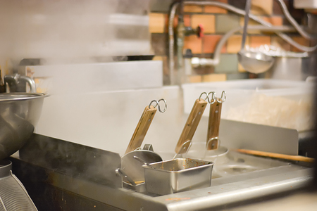 Noodle strainer basket with wood handle and warm stainless steel stock boiler pot with smoke.の写真素材