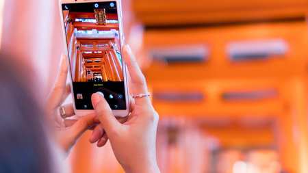 Kyoto, Japan - November 16, 2018 : Woman traveller taking photo Red Torii gates by your phone. Fushimi Inari shrine in Kyoto, Japanのeditorial素材